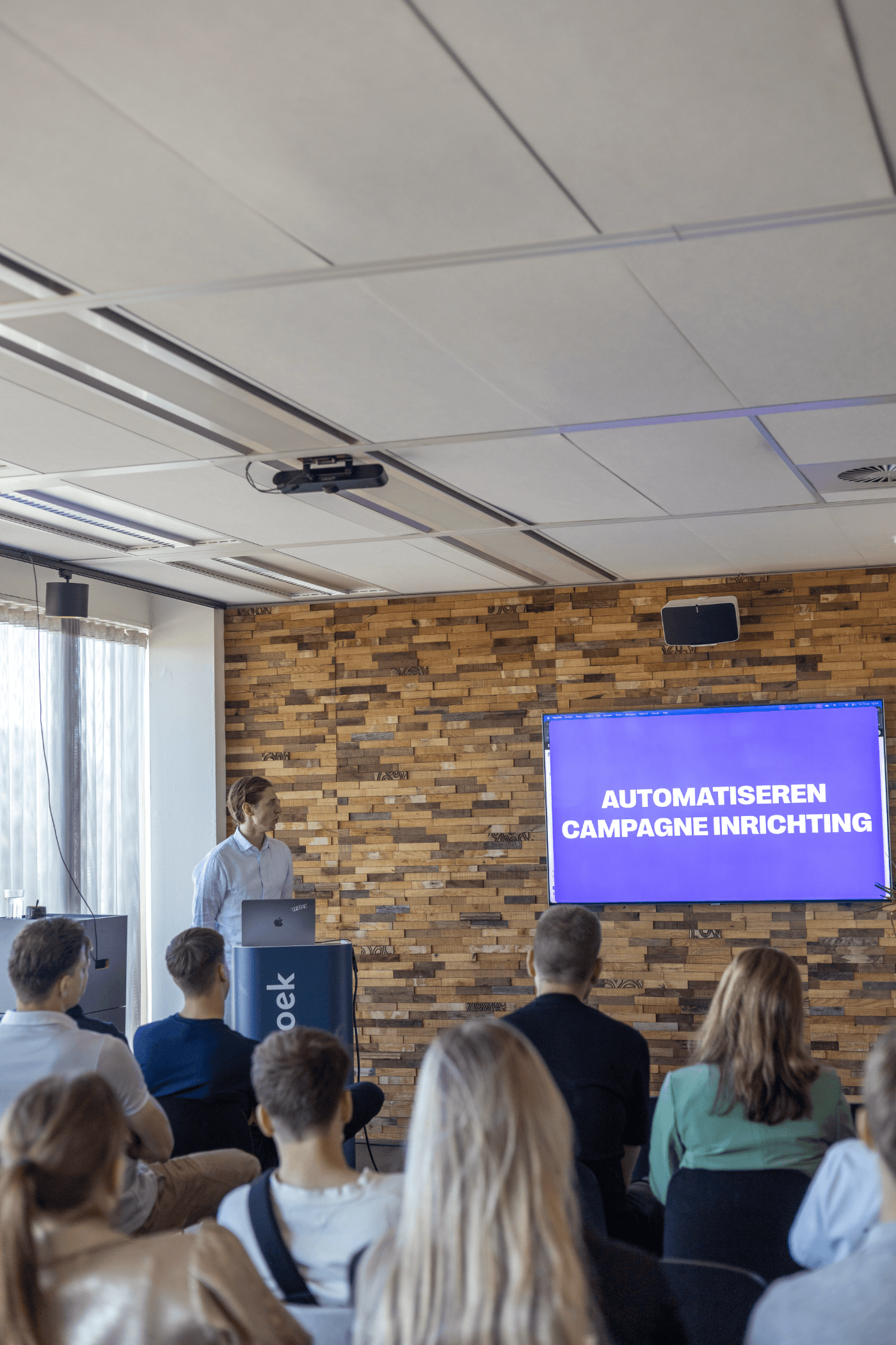 Melle geeft een interne AI-sessie bij Friday, op de schermen 'Automatiseren campagne inrichting'
